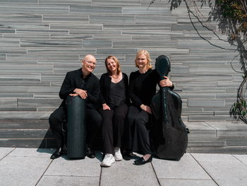 Tre musikere sitter på en steinbenk